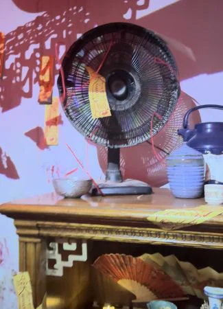 A physical fan inside the ritual room, surrounded by projected visuals.